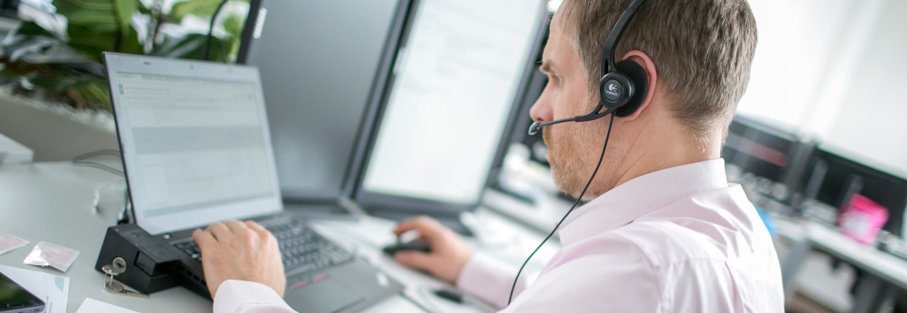 Person wearing headset looking at a screen and typing