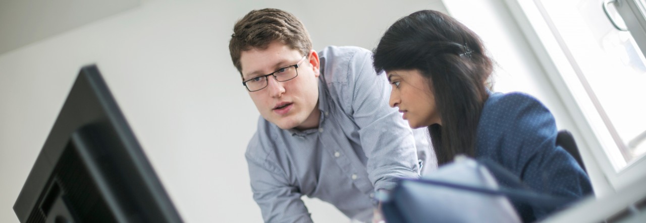 two people looking at a screen one explaining