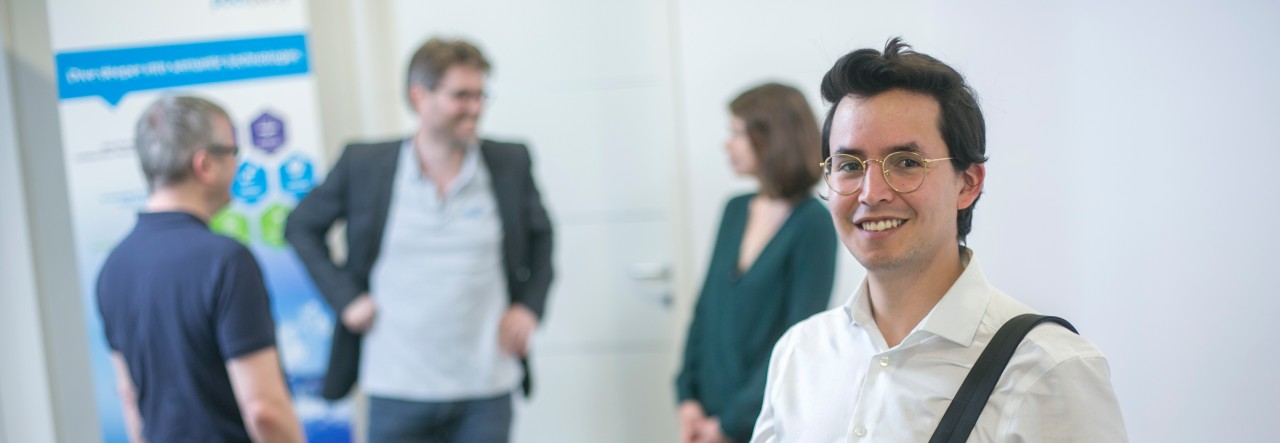 Smiling people in an office three talking in background one facing the viewer